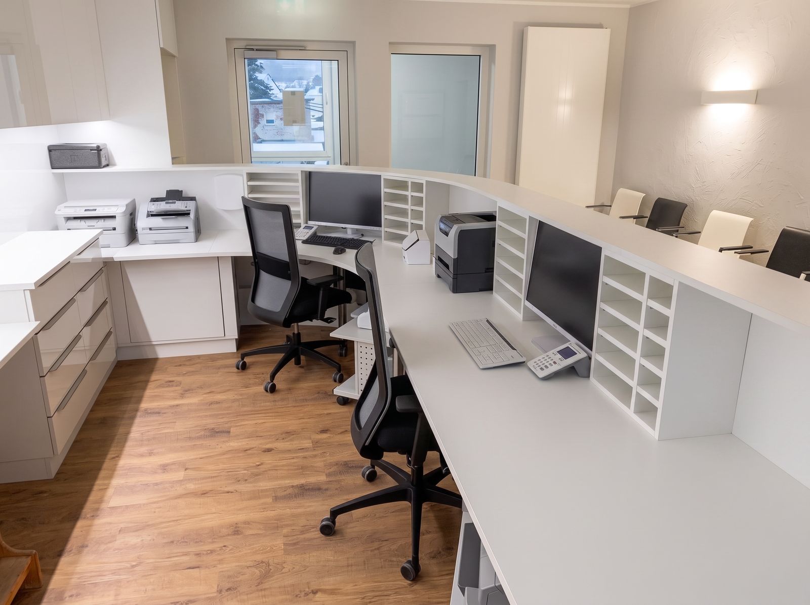 Apotheken-Backoffice mit weißen Arbeitsplätzen, Sortierfächern, Technik und Holzboden