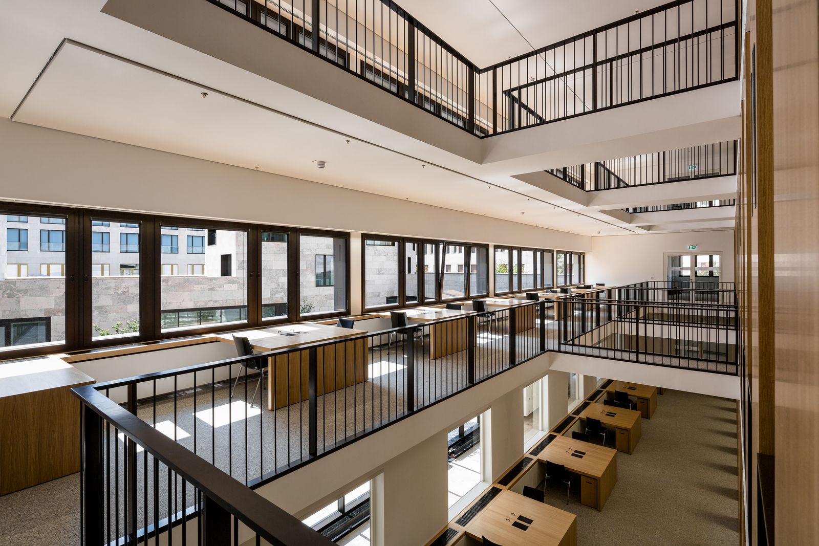 Leseplätze an Fenstern in einer mehrgeschossigen Bibliothek mit Holzverkleidung
