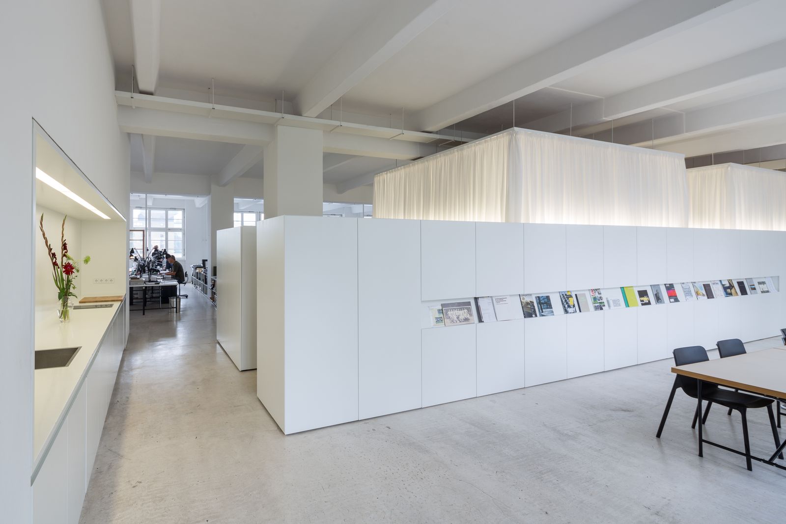Weiße Schrankwand mit Zeitschriftenauslage und Besprechungstisch im Büro